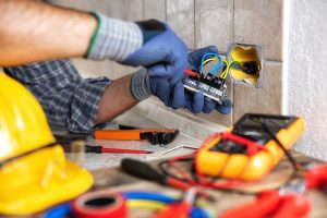 Electrician working on a project in a residential home with colorful cables and equipment on the counter. 