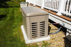 Residential standby generator on a concrete pad next to the deck 