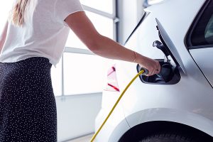 Closeup of a woman charging her electric vehicle in her garage. 
