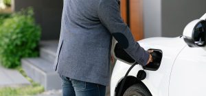 Closeup of a man in a suit charging his electrical vehicle at home 