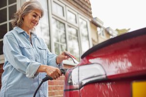 Woman charging her red EV at home. 