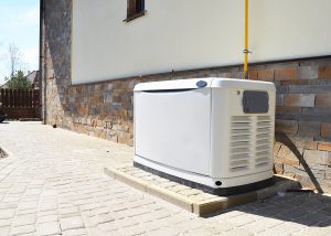 White generator installed on a brick patio on the side of a home. 