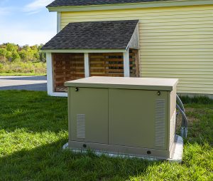 Standby generator installed on a concrete pad outside of a yellow home. 