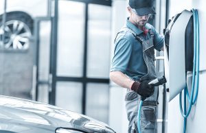 Male electrician testing and performing maintenance an EV charger station 