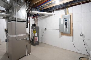 Residential basement with an electrical panel, how water heater, and furnace.