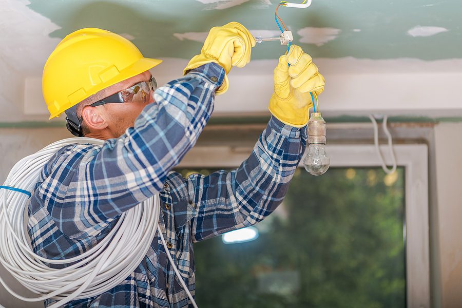 Male electrician working on a ceiling light upgrade. 