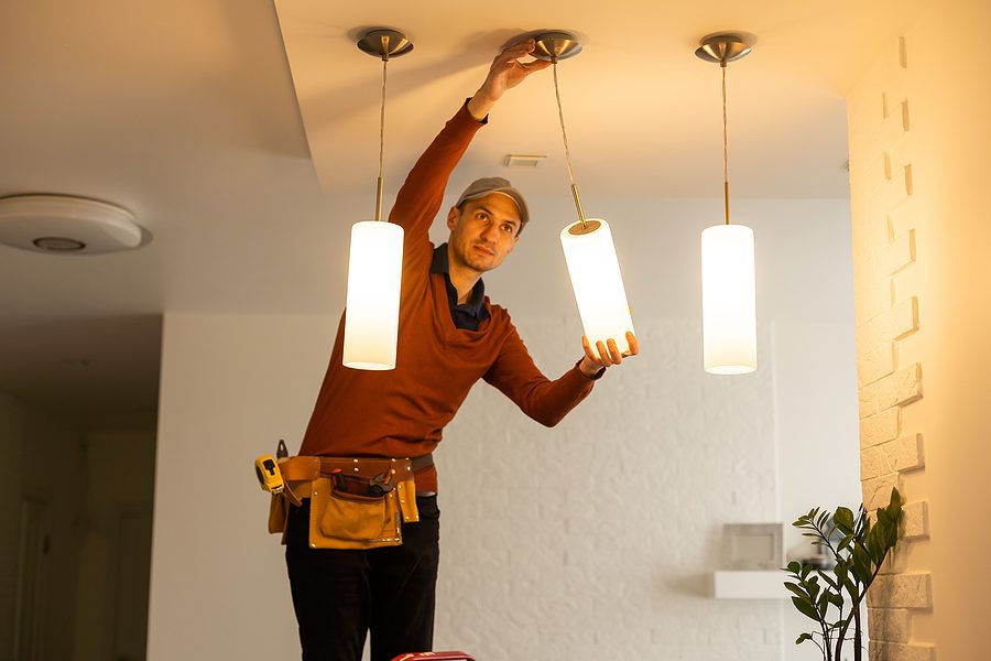 Electrician working on installing lights in a home. 