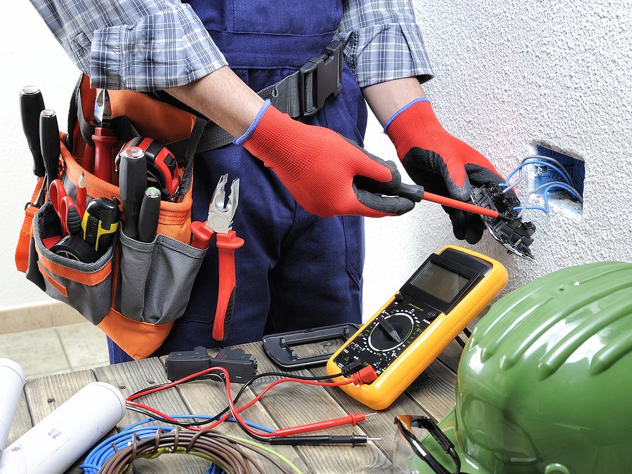 Closeup of an electrician replacing an electrical outlet. 
