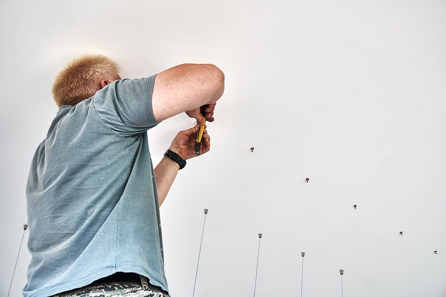 Closeup of an electrician installing lighting on a ceiling.